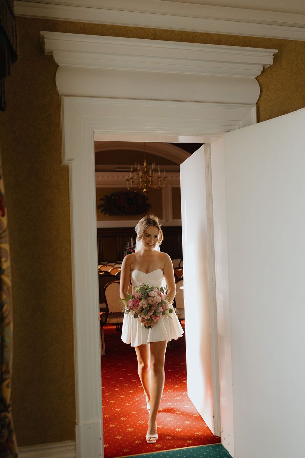 A series of elegant wedding photos showing a bride walking down a hallway with white pillars and red carpet.
