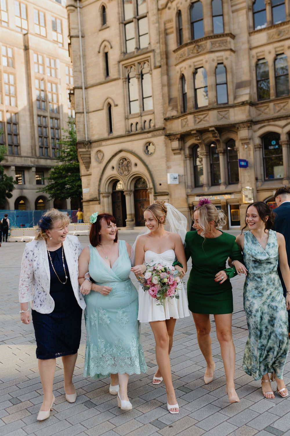 A group walking together outside a beautiful Gothic style building on a sunny day.