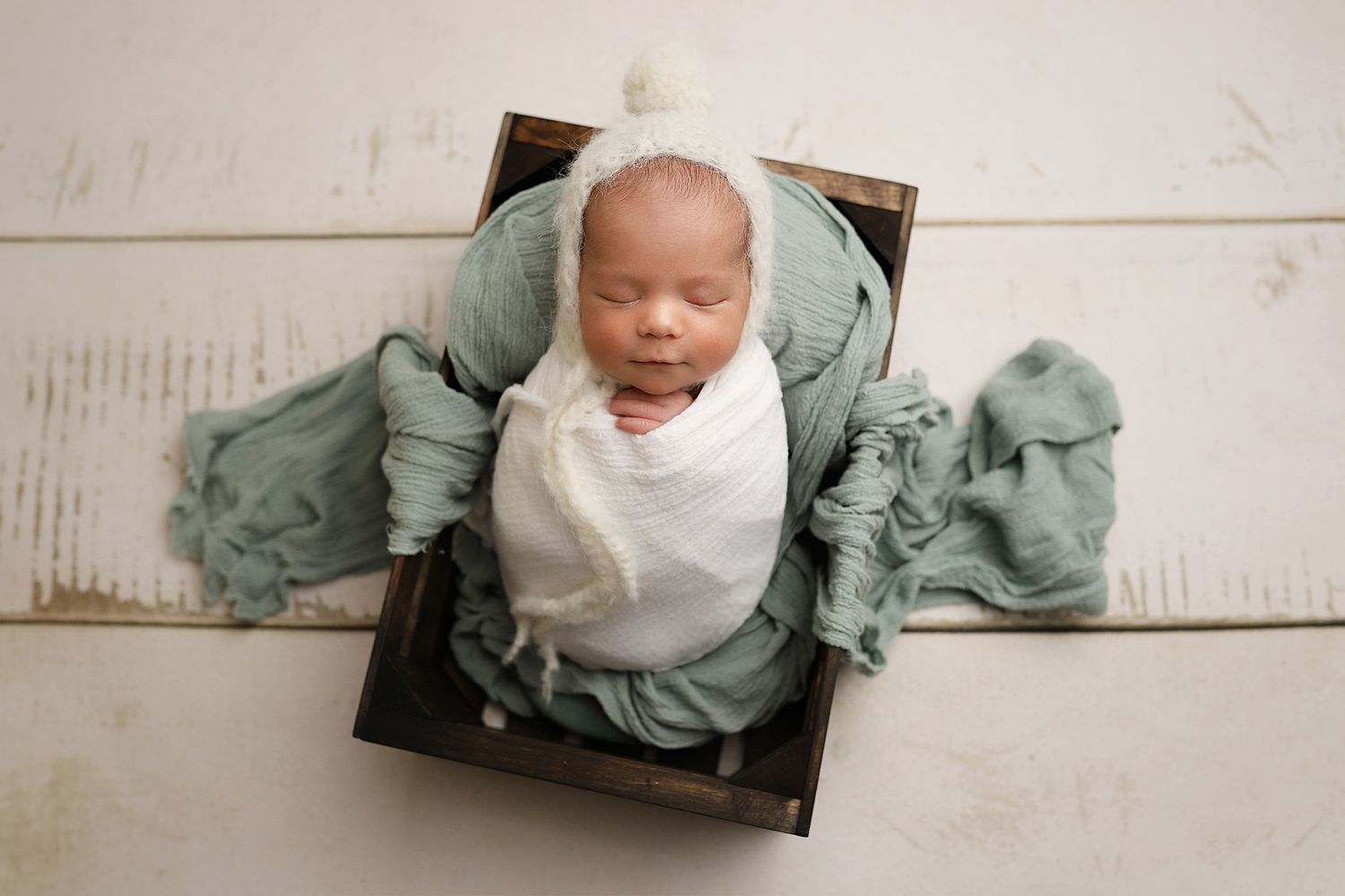 A series of five vintage-style newborn photos in soft sage green and cream tones against white backgrounds. Newborn photo studio in Utah.