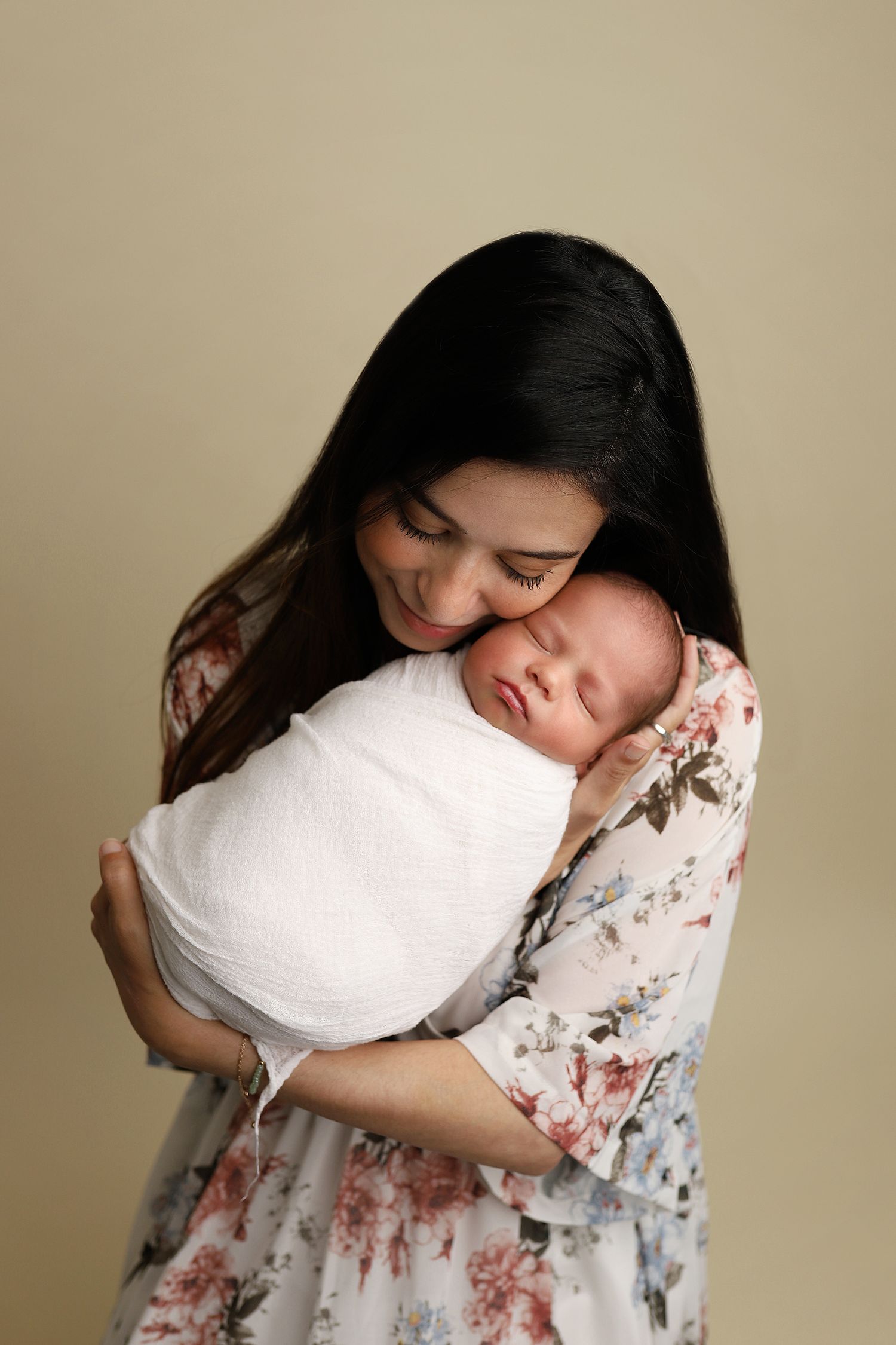 A series of photos showing someone hugging a white pillow while wearing a floral patterned dress against a beige background. Utah studio.
