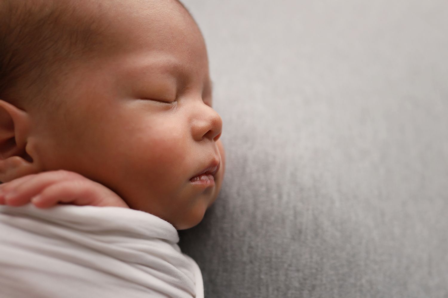 A sleeping baby lies peacefully on soft grey bedding in a series of connected photographs. Utah newborn photography