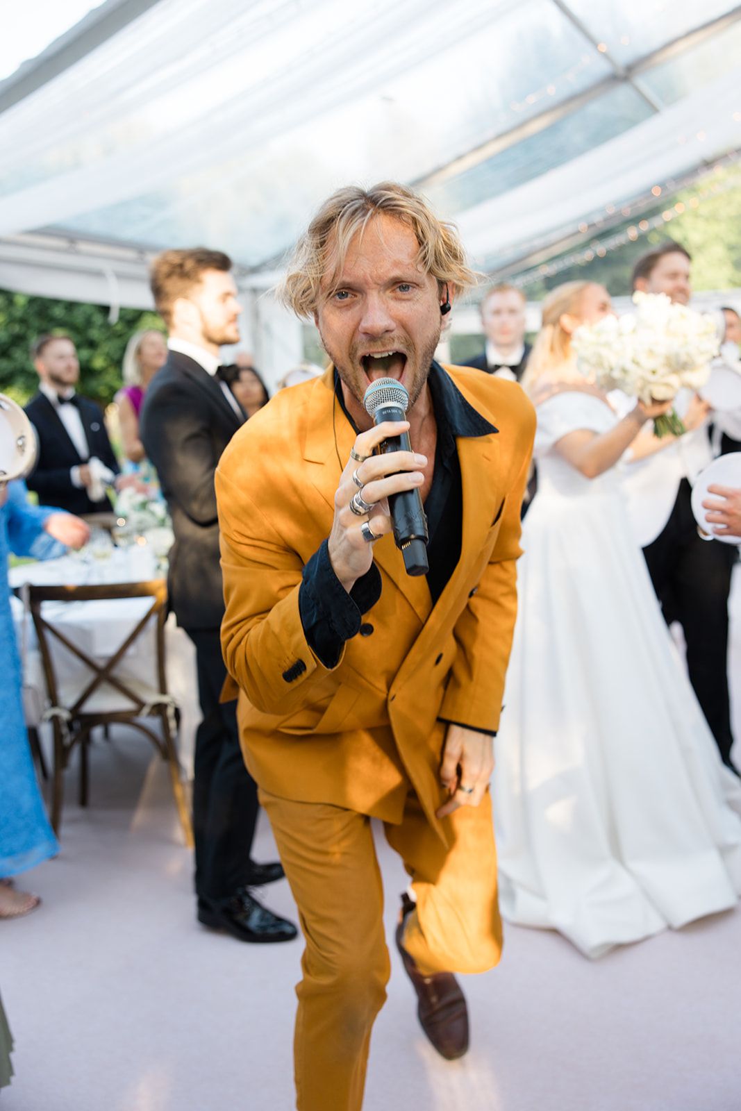 A person in a bright yellow suit performs a dramatic dance move on the wedding reception dance floor.