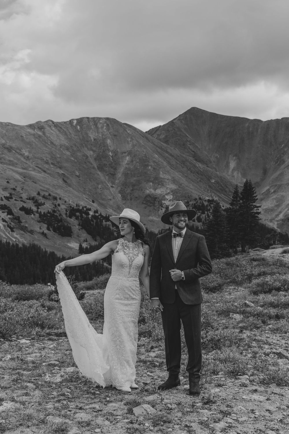 A couple walks along a scenic mountain ridge in black and white as the bride's dress flows in the wind.