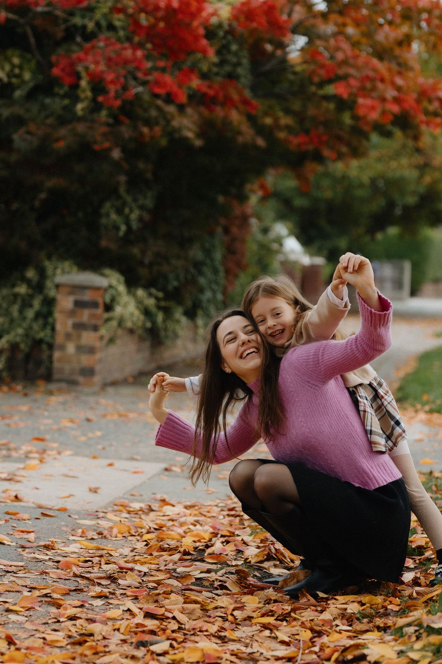 A series of candid photos showing joyful moments among autumn leaves with vibrant red maple trees overhead.