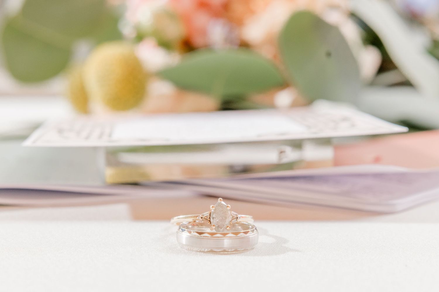 A close-up view of a delicate rose gold engagement ring with a sparkling center diamond on a soft blurred background.