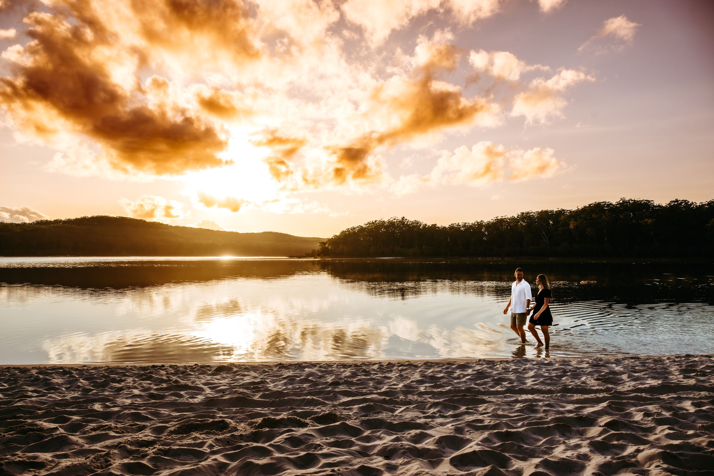 Silhouette of couple on beach during dramatic golden sunset.
