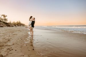 A couple sharing a romantic moment on a beach at sunset.