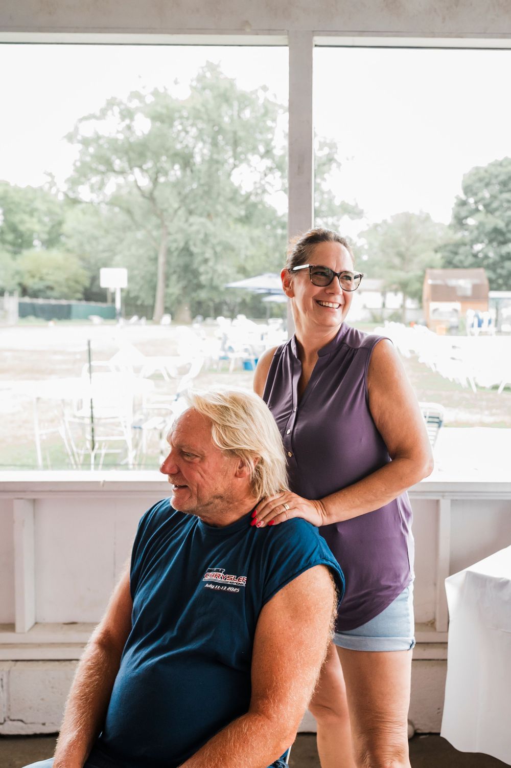 Two people sharing a cheerful moment on a covered porch with outdoor scenery visible.