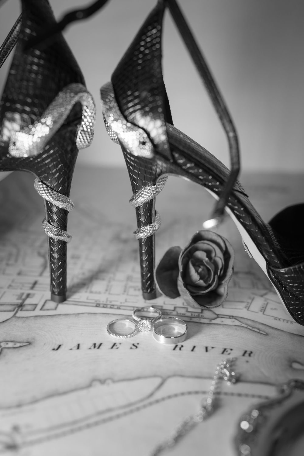 Wedding rings rest on an antique map showing James River in black and white photography.