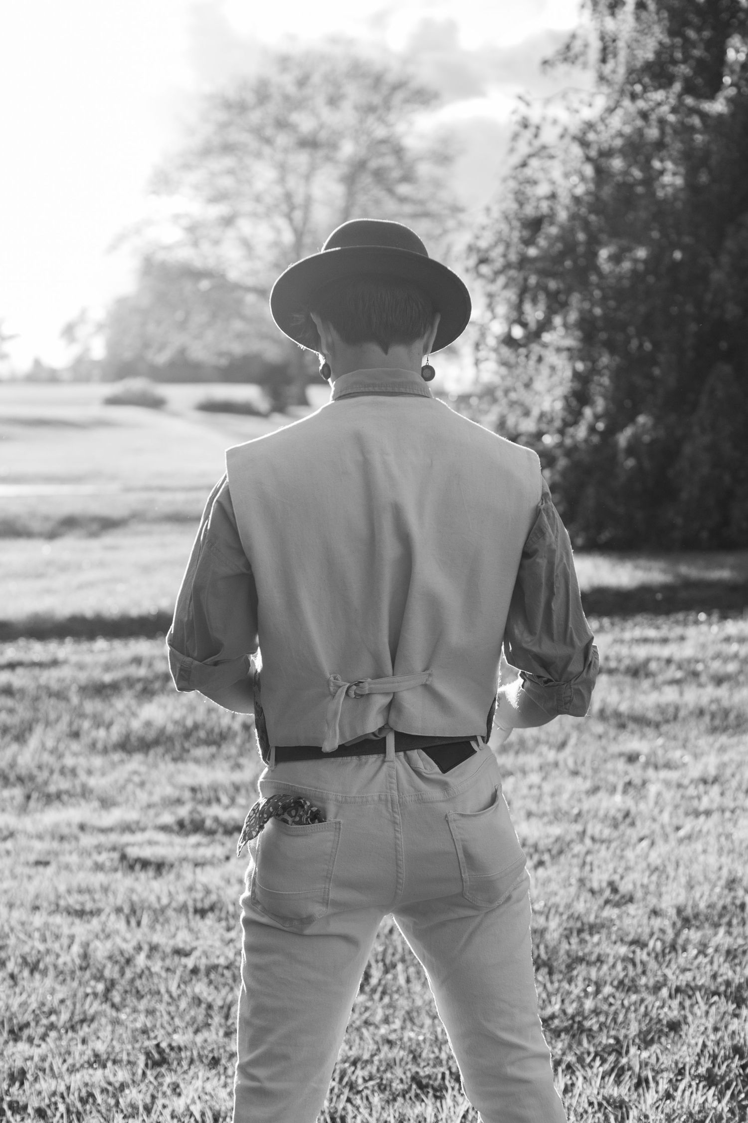 Black and white photo showing figure in western attire from behind.