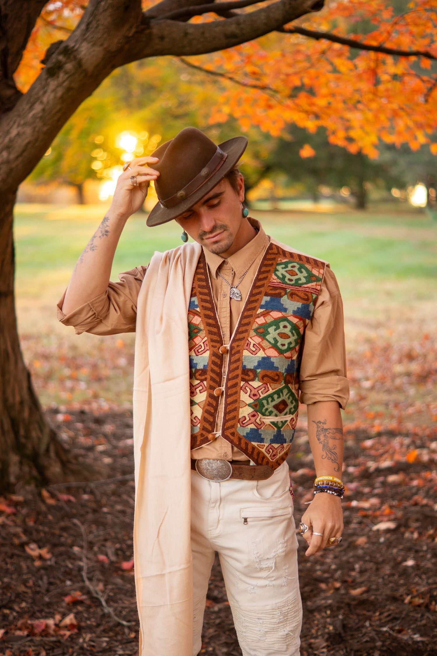 Autumn scene with western outfit against orange fall foliage and setting sun.