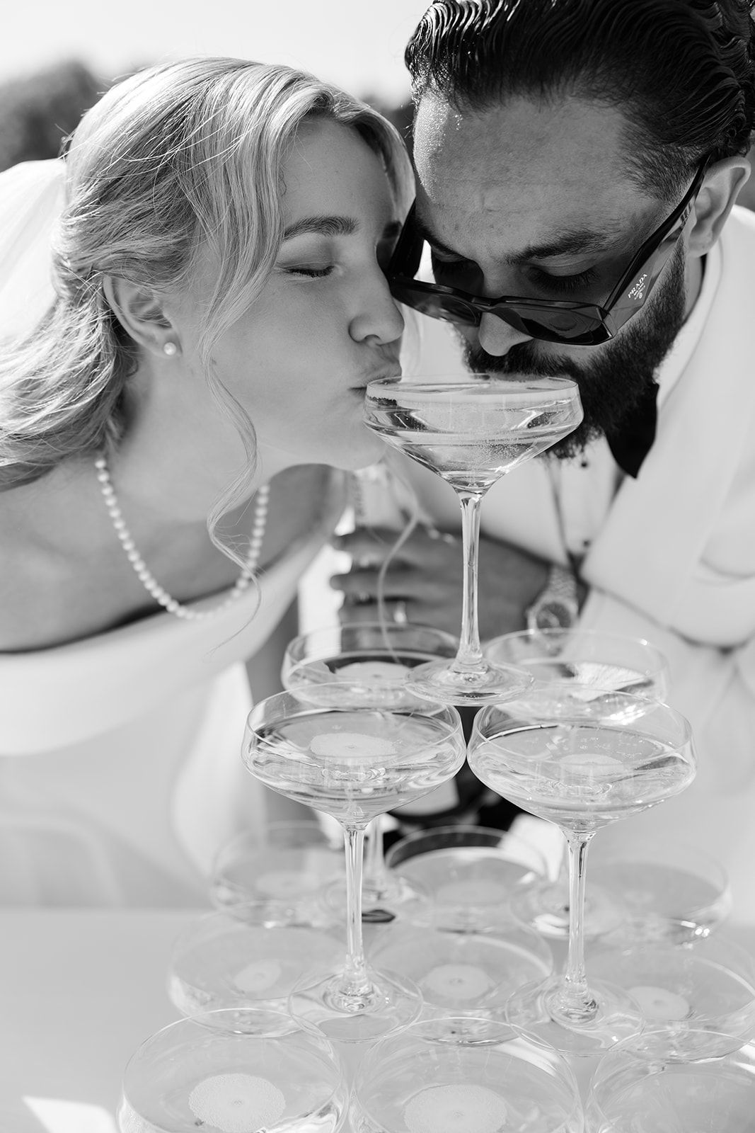 A romantic black and white photo series showing a couple drinking from a champagne tower.