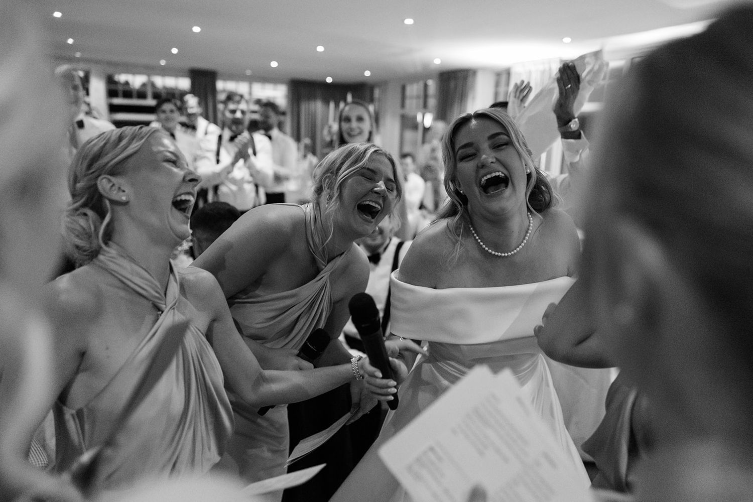 A series of candid black and white wedding photos showing joyful laughter and celebration during a reception.