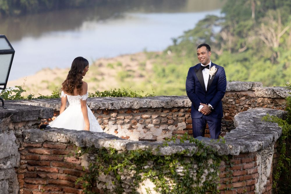 A couple shares a romantic moment at a scenic stone overlook by a lake during their wedding photoshoot.