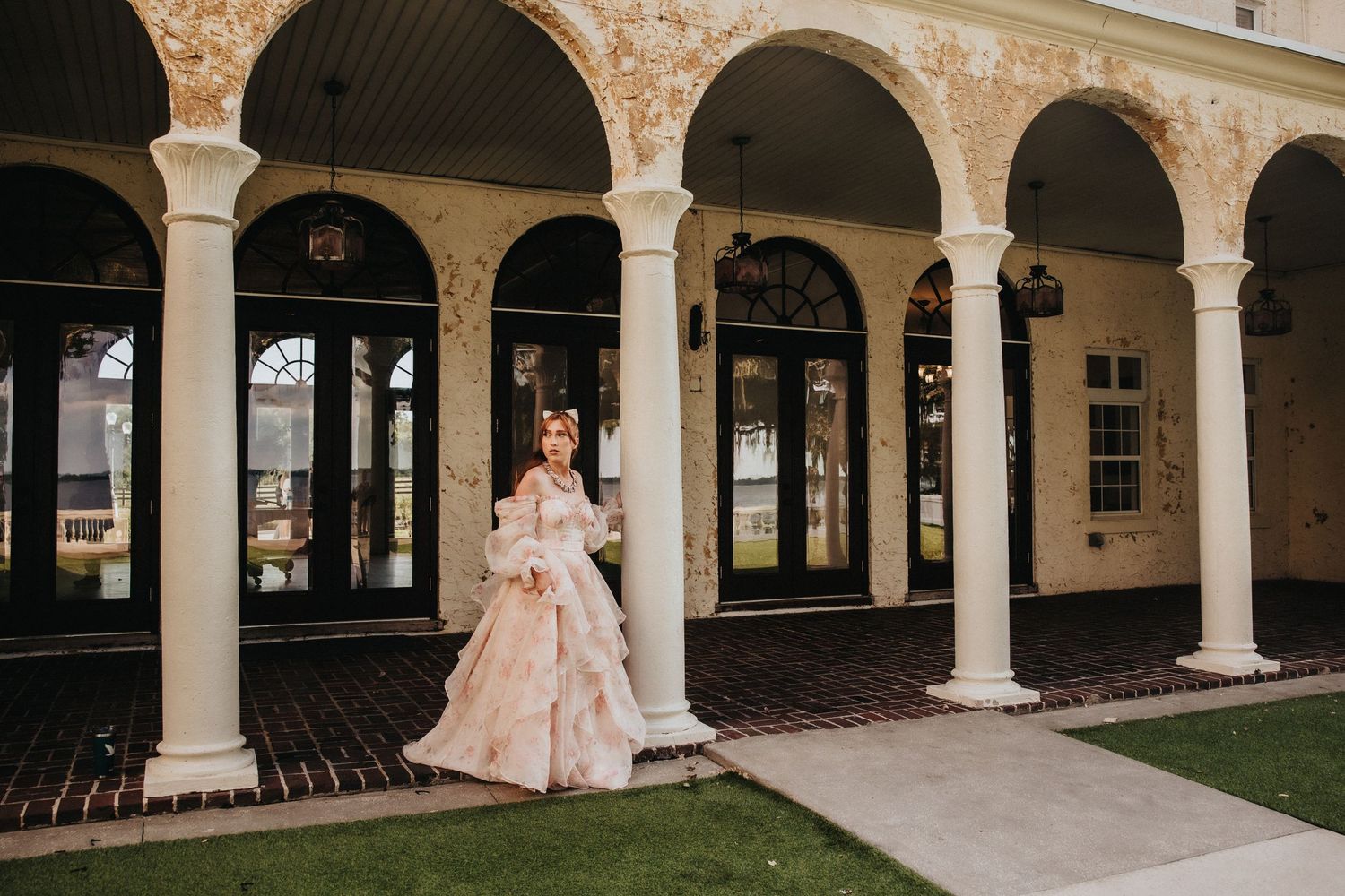 Elegant white wedding ceremony setup with floral arches and stone architecture at a luxurious venue.
