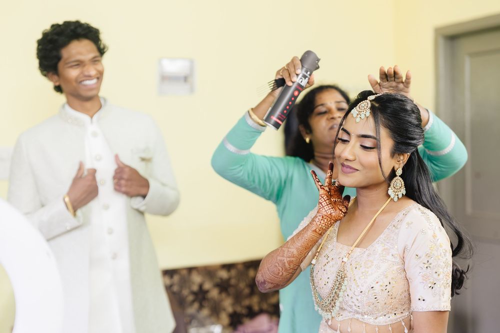 Bride getting ready with traditional Indian mehndi and bridal jewelry preparations in soft natural light.