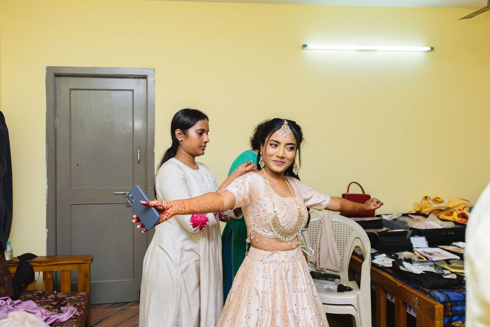 A person in a white dress adjusts their gown while getting ready in a room with yellow walls.