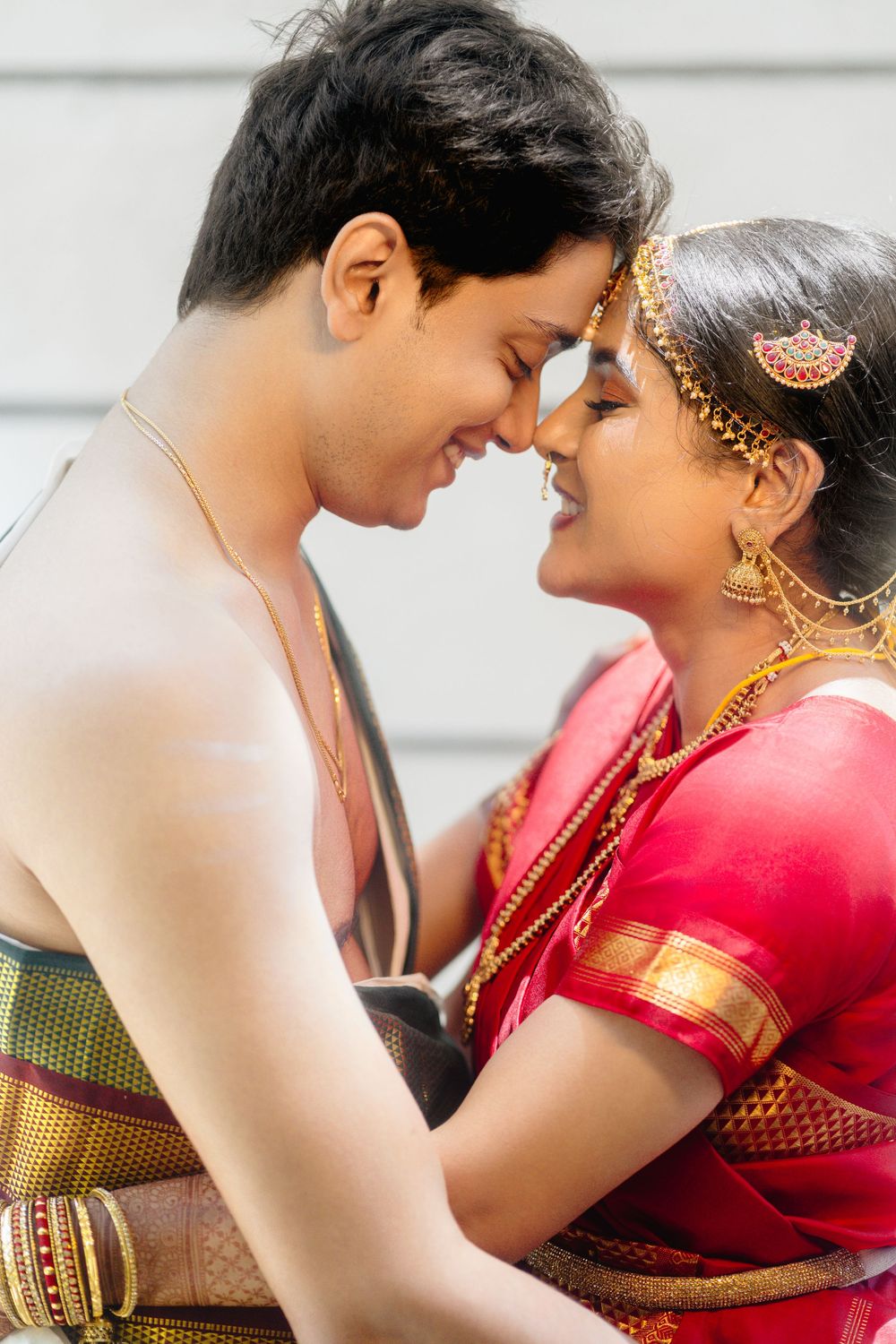 A romantic couple in traditional Indian attire share an intimate moment during a photo session.