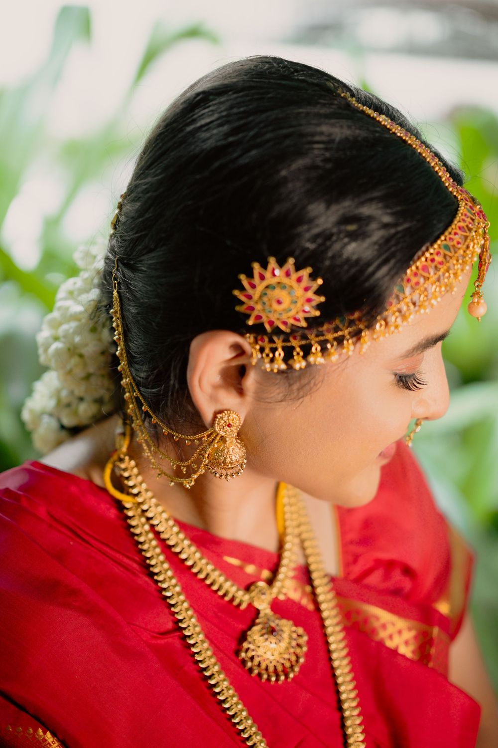 Close up of traditional South Indian bridal jewelry and hair accessories with red and gold details.