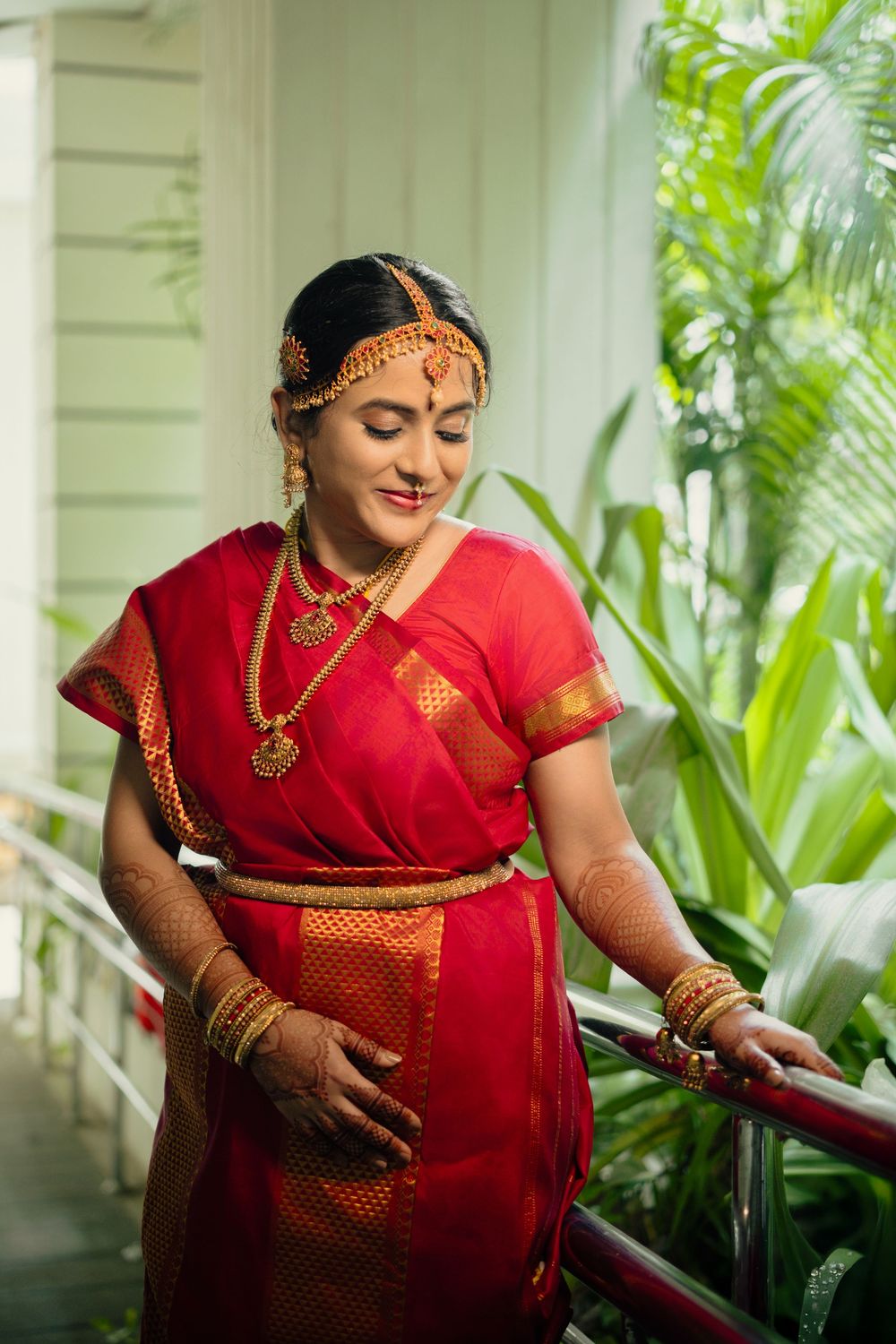 A series of four photos showing a person in traditional red Indian attire posing during a maternity photoshoot.