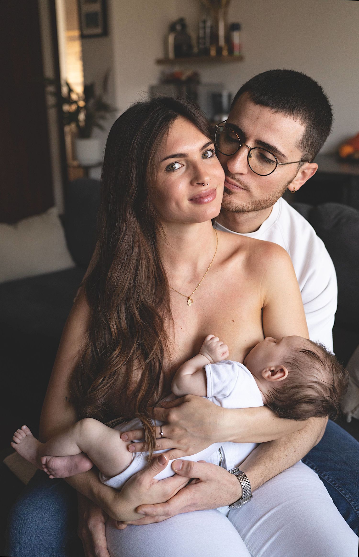 abbraccio di mamma e papà mentre mamma allatta al seno, bambino ciuccia il latte dalla mamma