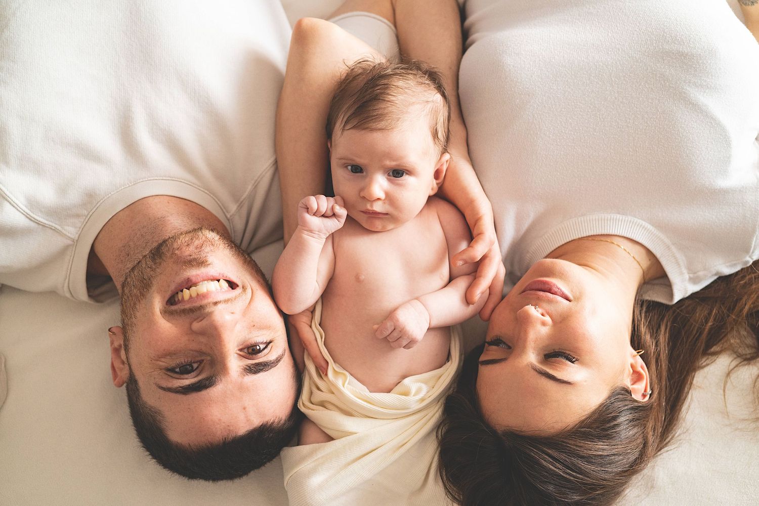 neonato tra mamma e papà, neonato con pugnetto