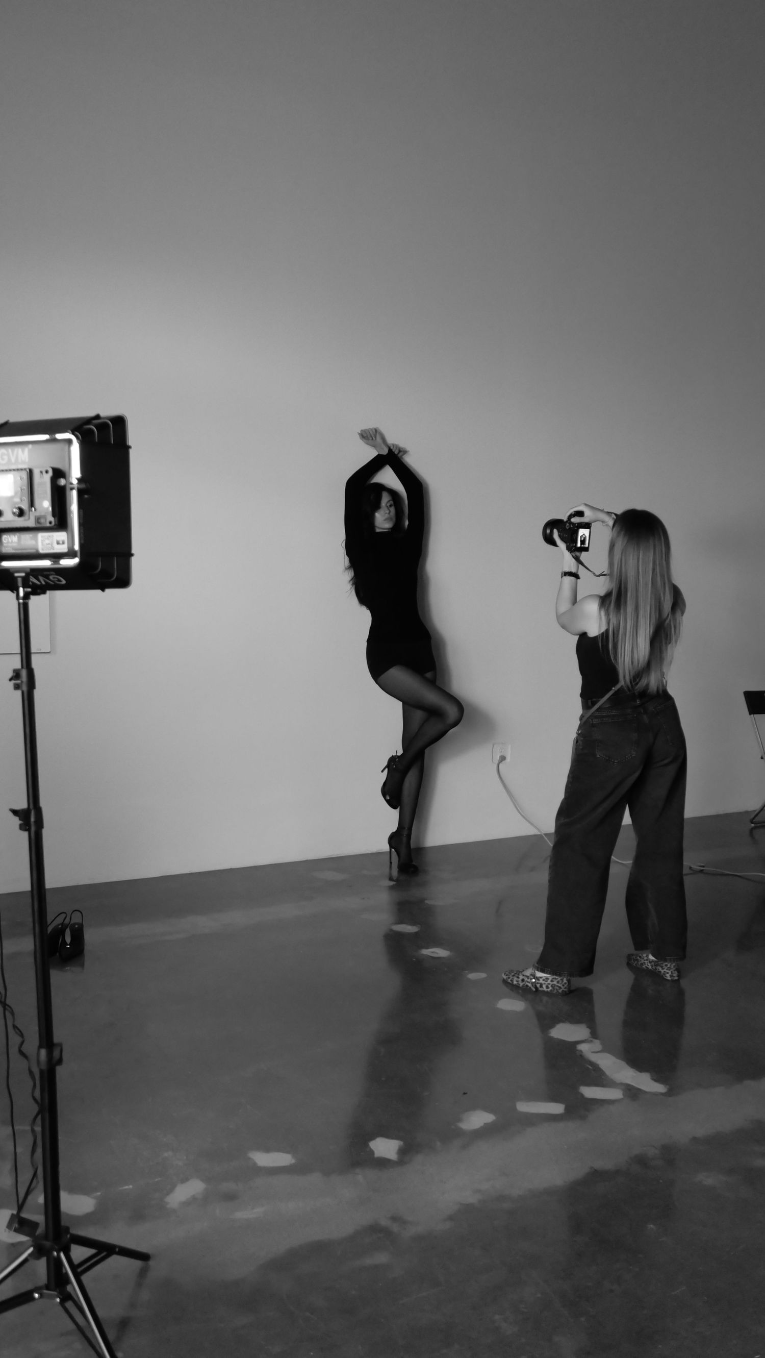 Black and white photo of people viewing small screens mounted on stands in a minimalist gallery space.