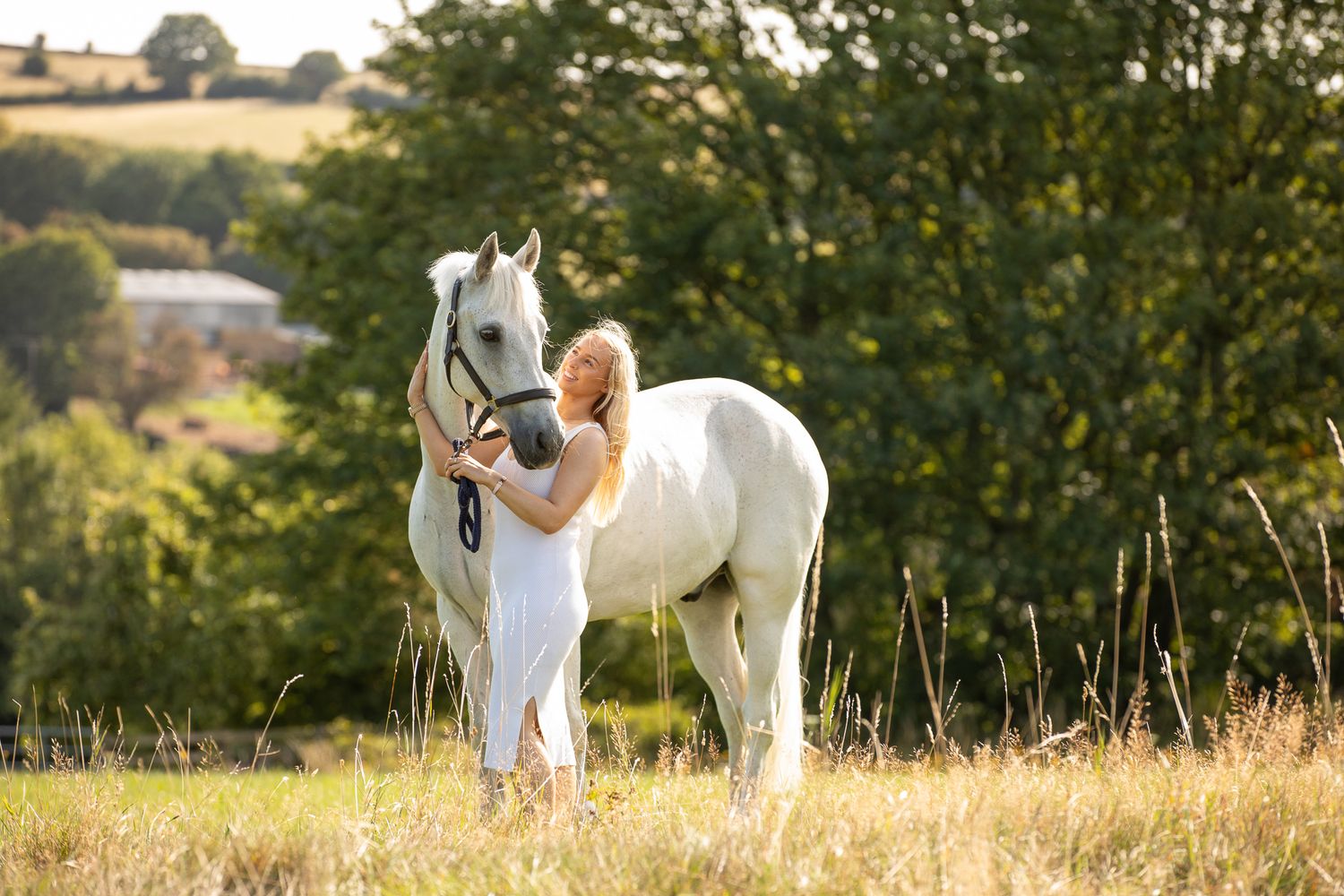 A horse and its rider enjoy an outdoor photoshoot session near rustic wooden fencing on a sunny day.