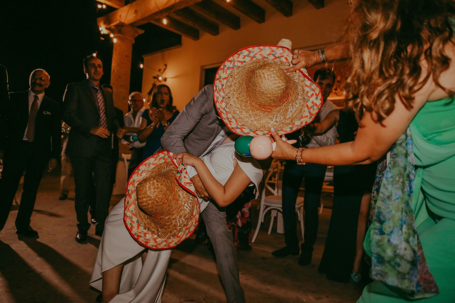 Two dancers wearing straw hats perform at a nighttime party venue with guests watching in the background.Pedregal Los Cabos Wedding
