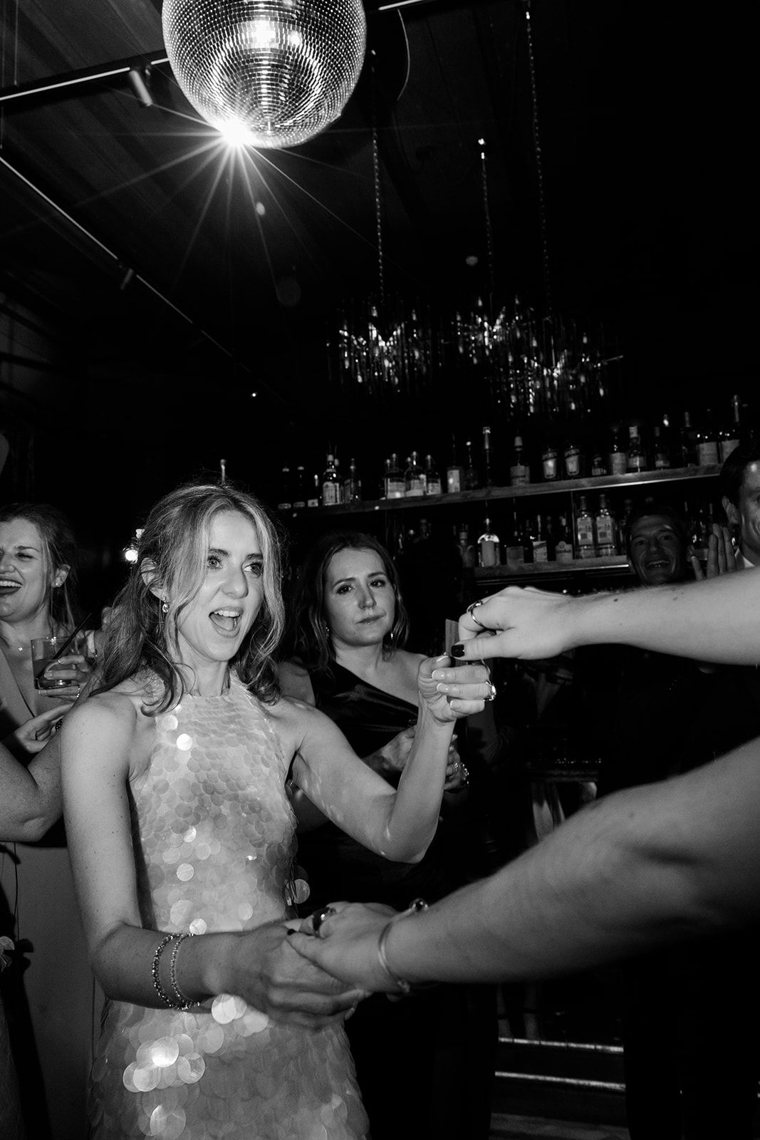 People dancing and celebrating under a disco ball at a nightclub in black and white photography.