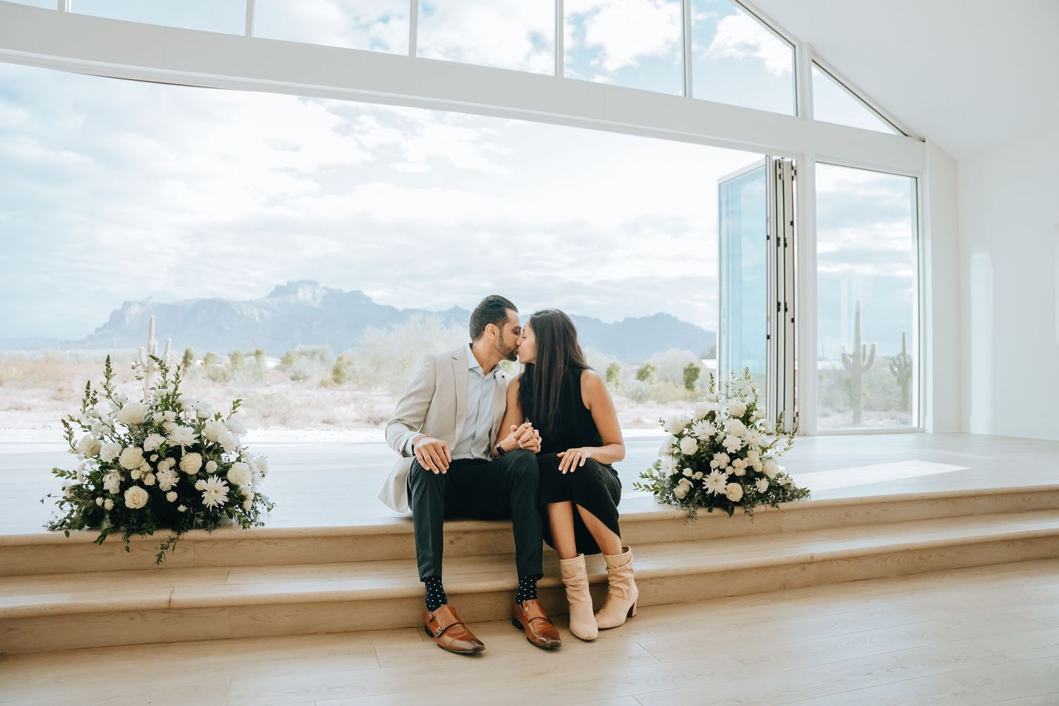 Minimalist white chapel interior with large windows overlooking desert landscape.