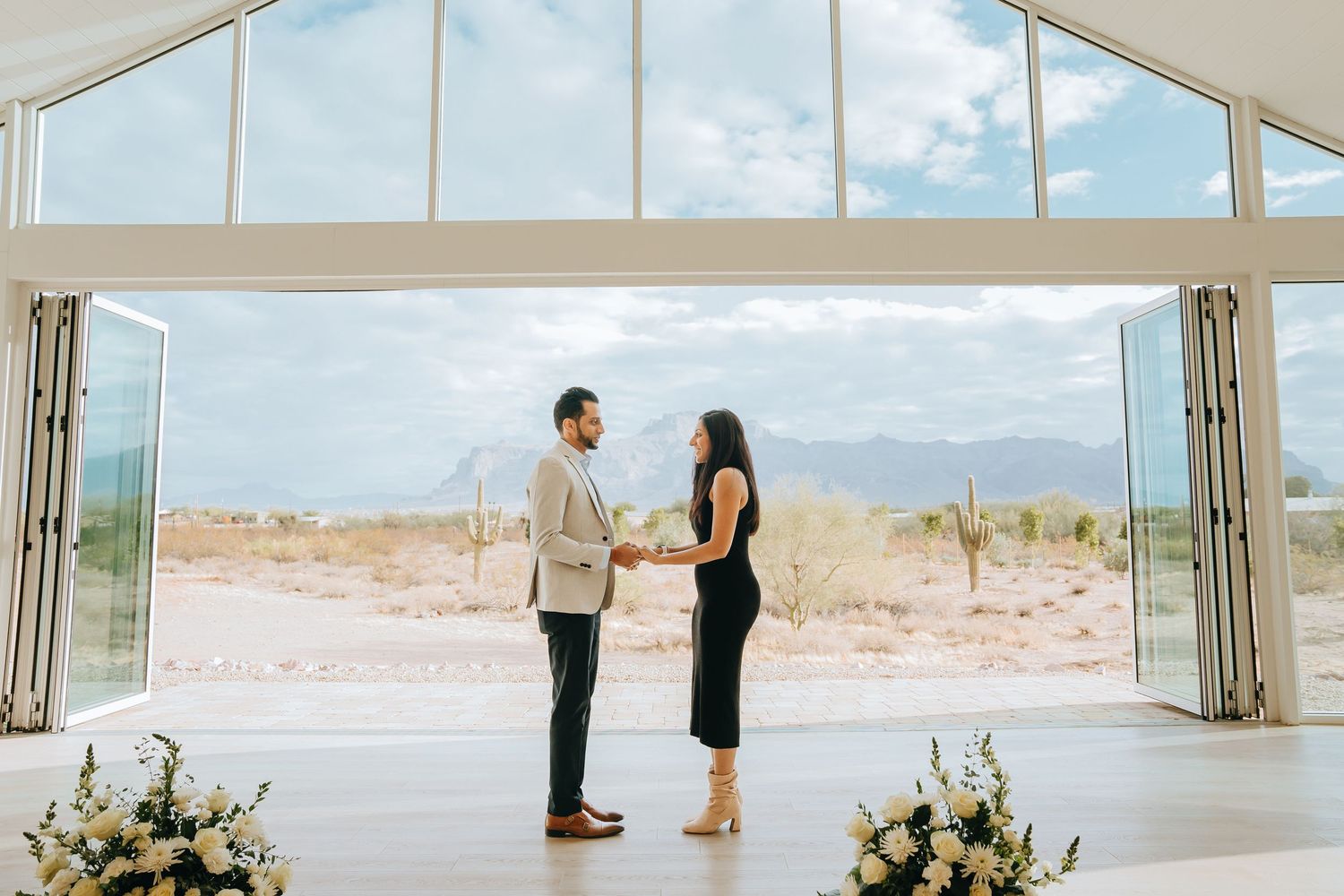 Panoramic view of a modern white chapel with desert mountains visible through large windows.