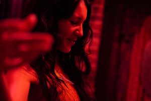 Artistic portrait bathed in red lighting showing a person in profile against dark background.