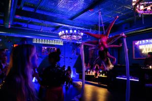 Aerial performance captured in a dimly lit nightclub with ornate chandeliers and blue ambient lighting.