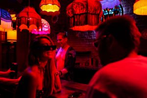 Red-lit bar interior with vintage-style pendant lamps hanging from the ceiling.