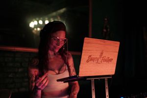 A wooden menu board or sign is illuminated by warm lighting in a dark venue.