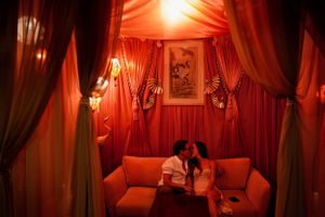 Intimate lounge setting with red draped fabric and mood lighting.