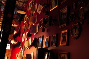 Red-tinted wall adorned with vintage frames and decorative elements in dim lighting.