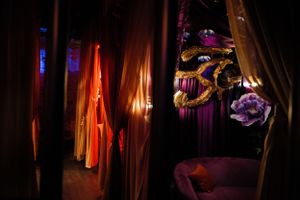 Dimly lit interior space with hanging fabric and decorative elements in moody purple and orange lighting.
