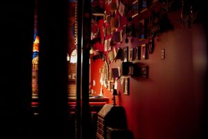 Dark atmospheric bar interior with red lighting and hanging decorations casting shadows.
