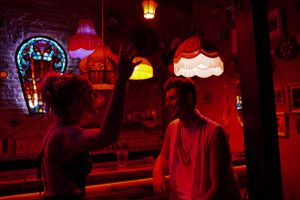 Bar scene with neon signs and red ambient lighting creating a moody atmosphere.