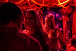 Crowd mingling under deep red lighting with neon accents in a nightclub setting.
