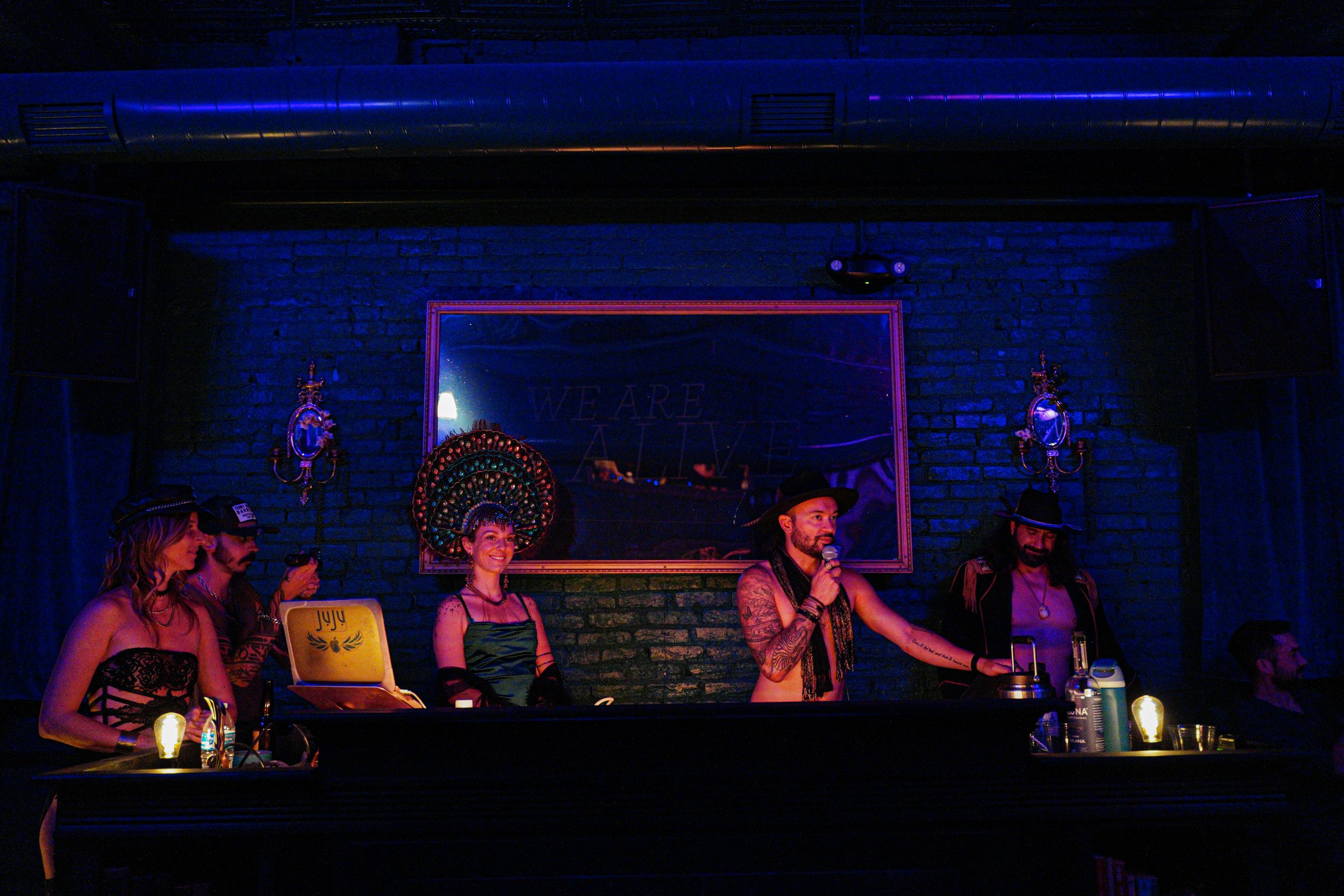 DJ booth and performers silhouetted against blue lighting at a nightclub.