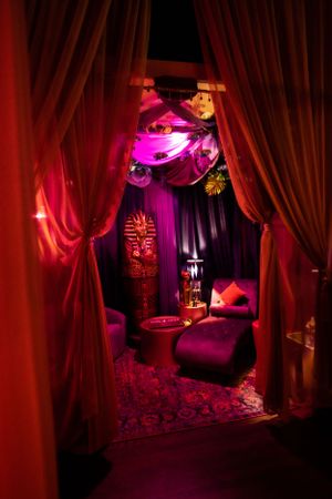 Luxurious lounge area with red curtains and purple lighting featuring Egyptian-themed decor.