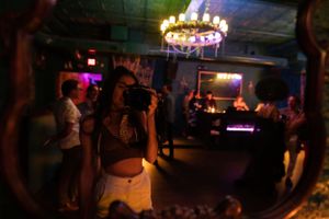 Nightclub scene with circular chandelier and colorful ambient lighting.