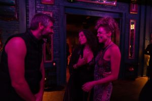 Nightclub interior illuminated by vibrant pink and purple lighting.