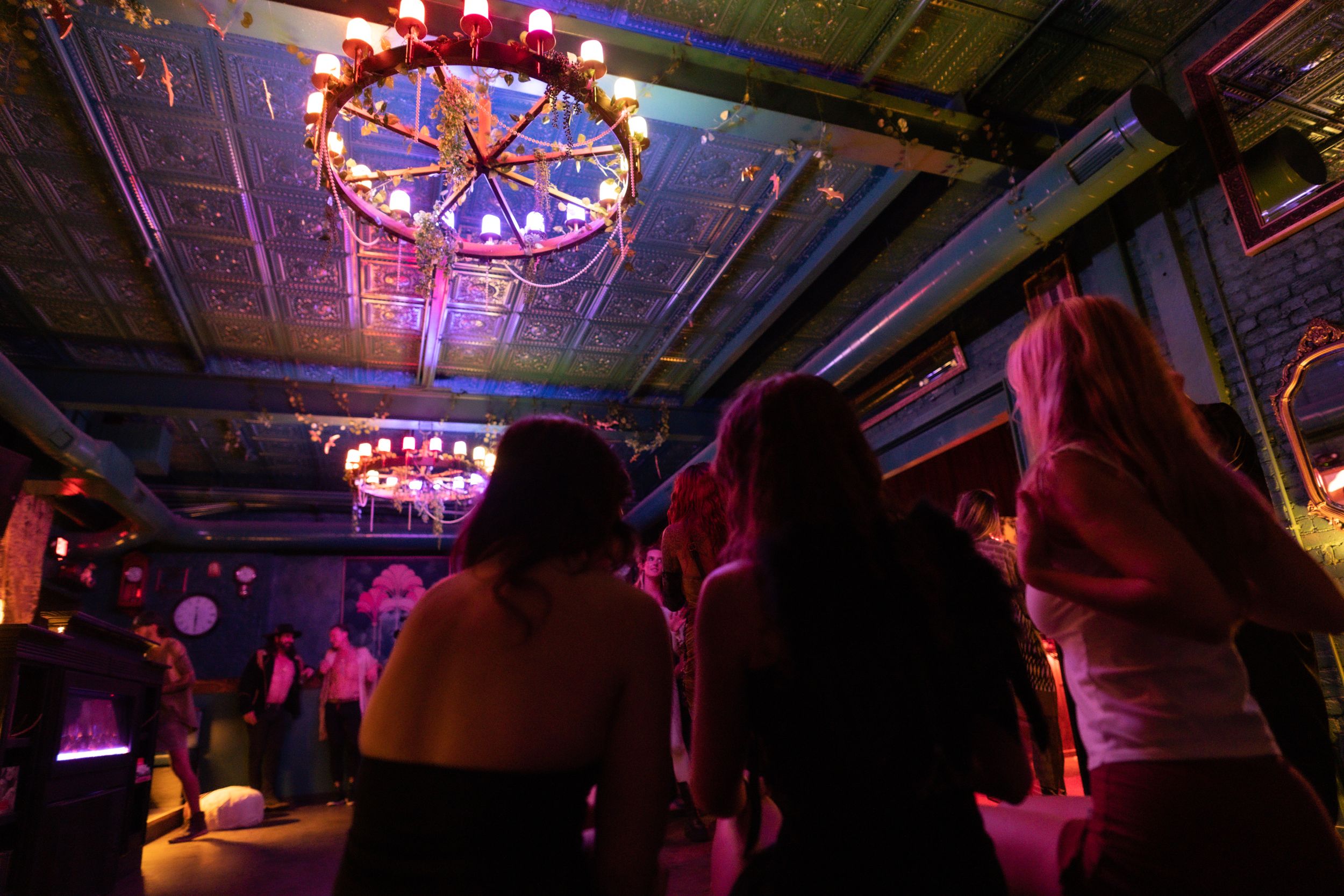 Dance floor under an ornate chandelier with colorful mood lighting.