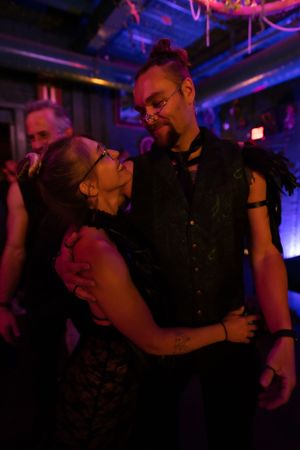 Couple dancing intimately under purple nightclub lights.