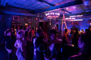 Dance floor filled with party-goers under blue lighting and vintage-style chandeliers.