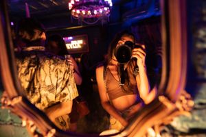 Dimly lit nightclub scene with colorful ambient lighting and people in silhouette.